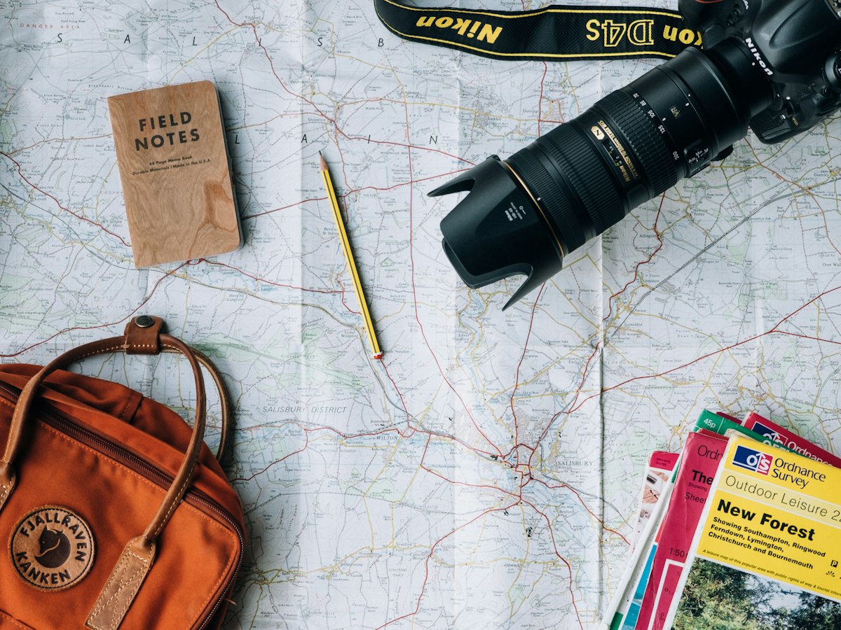 A paper map with a camera, field notes and a backpack